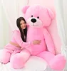 A young woman is hugging a large pink teddy bear on a bed. Anteprima dell’immagine prodotto