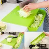 Limettenfarbenes Schneidebrett mit herausnehmbarem Behälter, in einer Küche gezeigt, wo Kohl gehackt und in eine Pfanne gegeben wird Anteprima dell’immagine prodotto