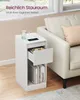 A white narrow nightstand with an open drawer and books on a shelf, placed next to a cream-colored sofa. Produktbild-Vorschau