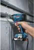 A hand holding a blue Bosch impact driver, drilling into a wall with pipes. Anteprima dell’immagine prodotto