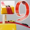 Rote Spielzeugauto-Strecke mit einer Schleife und zwei Spielzeugautos, einem gelben und einem schwarzen, auf grauem Hintergrund Anteprima dell’immagine prodotto