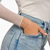 A woman's hand wearing two bracelets is placed in the pocket of her denim jeans. Anteprima dell’immagine prodotto