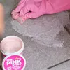 A hand wearing a pink glove is cleaning a textured surface with a pink paste. Produktbild-Vorschau