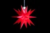 A red star-shaped decoration hangs against a black background. Produktbild-Vorschau