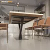 A dining table with a unique V-shaped black metal base, surrounded by chairs in a modern dining room setting. Voir les images du produit