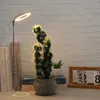 A ring-shaped LED plant grow light is positioned next to a potted cactus and some books on a desk. Náhľad obrázku produktu