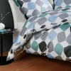 A close-up view of a geometric patterned duvet cover and pillowcase set on a bed. Produktbild-Vorschau