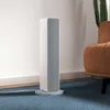 A white and gray Xiaomi Smartmi Fan Heater is placed on a blue carpet next to a white wall and a brown armchair. A cactus is visible in the background. Voir les images du produit