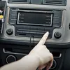 A hand is plugging an audio cable into a car's stereo system. Anteprima dell’immagine prodotto