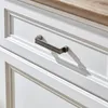 A close-up view of a white cabinet drawer with a metal handle and a wooden countertop. Produktbild-Vorschau