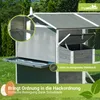A close-up view of a grey wooden chicken coop with a metal tray extended, set in a grassy outdoor environment. Produktbild-Vorschau