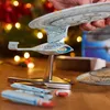 A hand holding a model starship with a Christmas tree in the background. Podgląd zdjęcia produktu