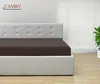 A bed with a brown fitted sheet and a white tufted headboard in a room. Produktbild-Vorschau