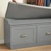 A person's hand is placing a grey cushion on top of a grey storage bench with drawers. Náhľad obrázku produktu