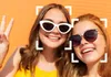 Two young women smiling and taking a selfie outdoors. Anteprima dell’immagine prodotto