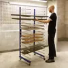 A man is placing a shelf onto a drying rack in a workshop. Anteprima dell’immagine prodotto