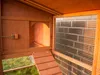 Interior view of a wooden chicken coop with a ramp leading to an opening and a mesh window. Produktbild-Vorschau