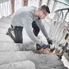 A man is using an angle grinder on a staircase. Produktbild-Vorschau