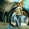 A young boy stands on a scooter in an aquarium tunnel. Voir les images du produit