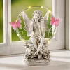 A solar-powered fairy figurine with butterflies and LED lights sits on a windowsill. Produktbild-Vorschau