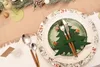 A Christmas-themed table setting with cutlery, plates, and festive decorations. Produktbild-Vorschau