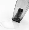 A close-up shot of a clear plastic container with a black filter mechanism, tipped over and leaking liquid onto a white surface. Produktbild-Vorschau