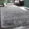 A close-up, angled view of a fluffy gray rug in a living room setting. Produktbild-Vorschau