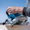 A person is using a Bosch cordless circular saw to cut a piece of wood outdoors. Podgląd zdjęcia produktu