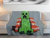 A Minecraft Creeper character and TNT blocks are printed on a gray blanket draped over a sofa. Produktbild-Vorschau