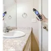 A hand holds a device in a bathroom near a sink and mirror. Produktbild-Vorschau