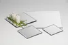 Several square and rectangular mirrors are arranged on a white surface, with two lit candles and some green foliage on one of the mirrors. Produktbild-Vorschau