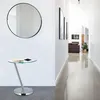 A hallway with a round mirror and a glass-top side table. Voir les images du produit