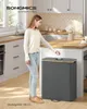 A woman is putting something into a large, dark gray laundry hamper with a wooden lid in a modern kitchen. Produktbild-Vorschau