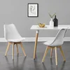 Two white dining chairs with wooden legs are placed around a white dining table in a room with gray walls. Podgląd zdjęcia produktu