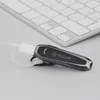 A close-up shot of a black Bluetooth headset resting on a light gray surface, with a portion of a white keyboard visible in the background. Náhled obrázku produktu