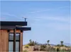 A modern building in a desert landscape with a Starlink dish on the roof. Produktbild-Vorschau