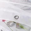 Close-up of a white curtain with a metal grommet and a metal clip attached. Produktbild-Vorschau