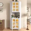 A white corner cabinet with glass doors and gold accents, decorated with flowers and other items, is shown in a room with a clock and a floor lamp. Produktbild-Vorschau