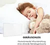 A child sleeping peacefully in bed with a teddy bear, with a white heating panel in the foreground. Produktbild-Vorschau