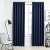 A pair of navy blue curtains hanging in front of a window, with a floor lamp and a chair to the left, and a shelf with decorative items to the right. Náhľad obrázku produktu