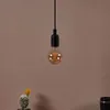 A single light bulb hanging from a black cord against a plain brown background. A small cactus with a yellow flower is visible in the bottom left corner. Produktbild-Vorschau