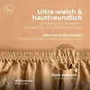 Close-up of a sand-colored fitted sheet with text overlays highlighting its features. Produktbild-Vorschau