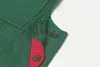 Close-up of a green garment with red accents and buttons. Náhľad obrázku produktu