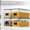 Four clear plastic food storage containers stacked on a white shelf, filled with different dry goods like oats, spaghetti, cereal, and pasta. Each container has a black label with white text identifying the contents. Produktbild-Vorschau