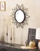 A sunburst mirror hangs on a textured wall above a dark dresser, adorned with candles and decorative items. Produktbild-Vorschau