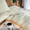 A cozy bedroom scene with a beige quilted bedspread and a cup of coffee on a tray. Produktbild-Vorschau
