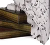 A close-up view of a white owl figurine perched on a stack of books. Produktbild-Vorschau