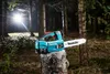 A teal Makita cordless chainsaw rests on a tree stump in a forest setting, with a bright light source in the background. Náhled obrázku produktu