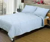 A neatly made bed with a light blue comforter and two pillows. Podgląd zdjęcia produktu