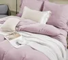 A neatly made bed with pink bedding, a white knitted throw, and a magazine and teacup. Podgląd zdjęcia produktu